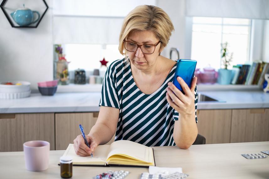 Woman in kitchen writing in journal