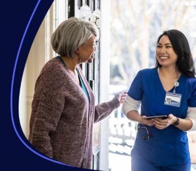 A women opening her front door to a smiling nurse. 