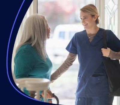 A women opening her front door to a smiling nurse. 