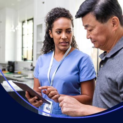A nurse reviewing health charts with a man in his own kitchen at home