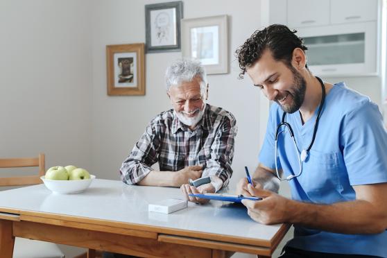Healthcare worker and patient sitting at table in home