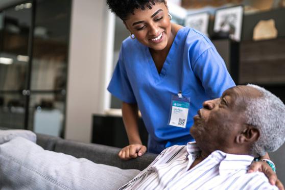 Home nurse talking to senior male on the couch