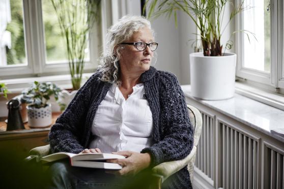 Woman sitting with book looking out a window